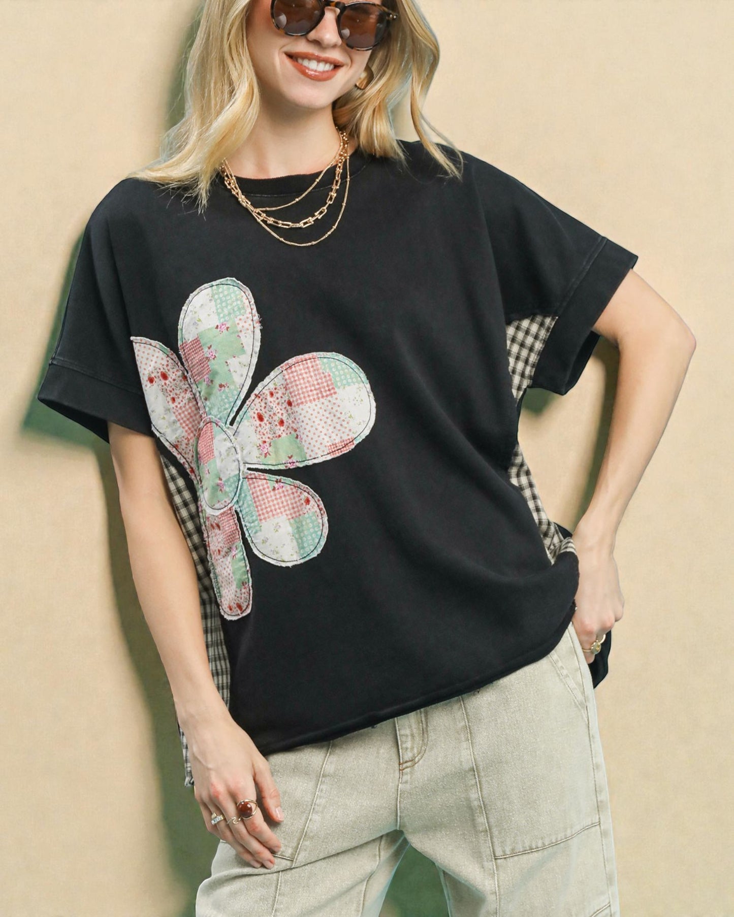Woman wearing a black t-shirt with a colorful butterfly design on a beige background
