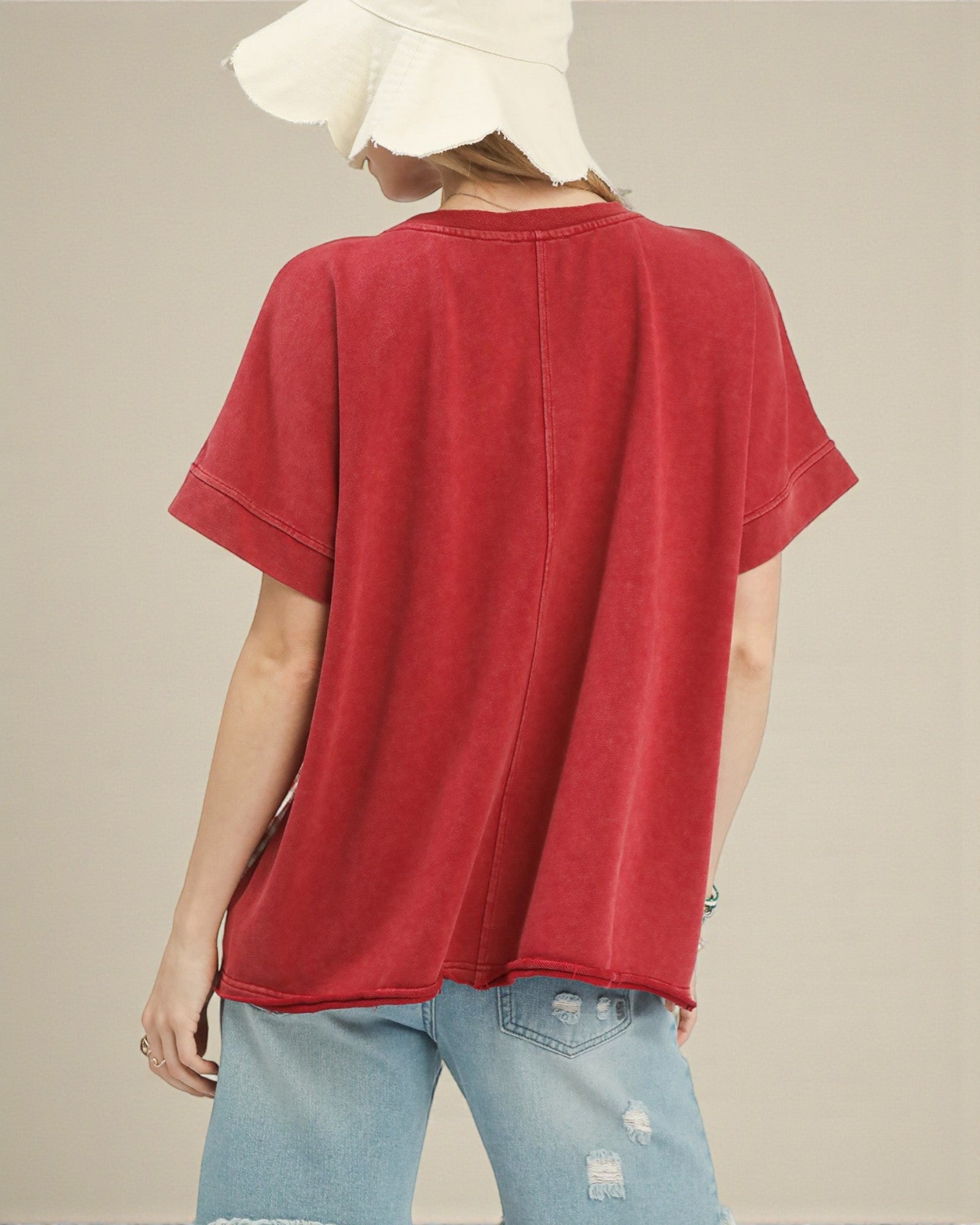 Person wearing a red t-shirt and light blue jeans with a beige background