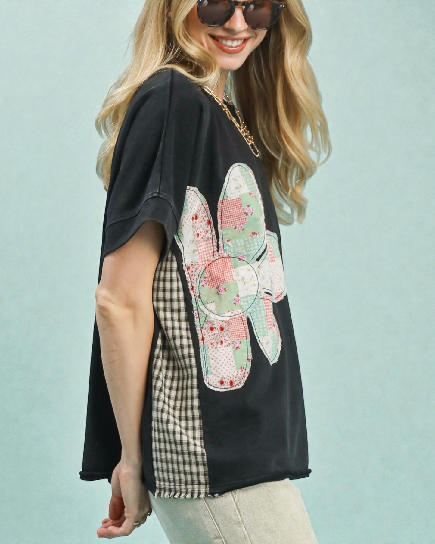 Woman wearing a black t-shirt with a colorful butterfly design on a light blue background
