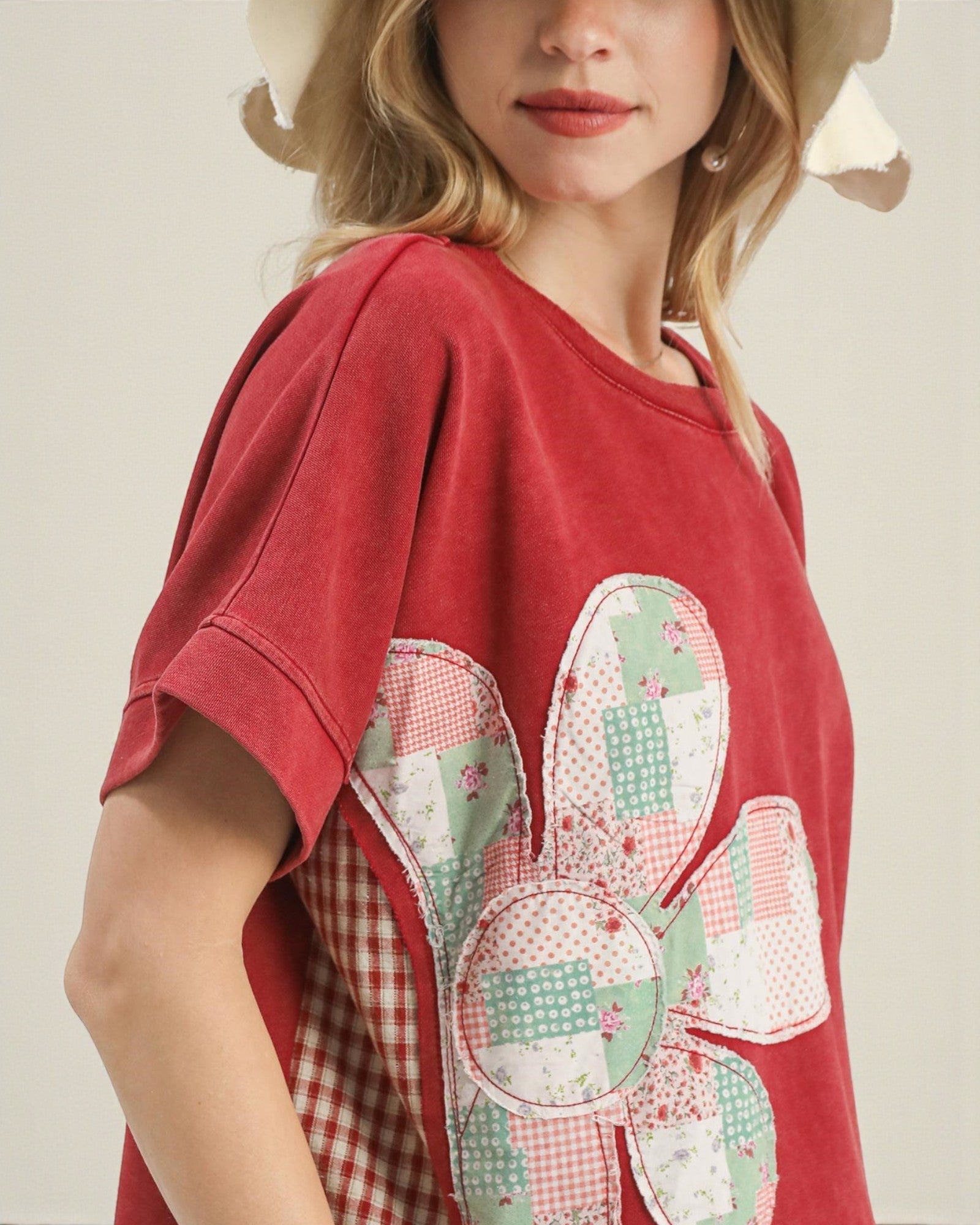Red t-shirt with a colorful patchwork design worn by a person.