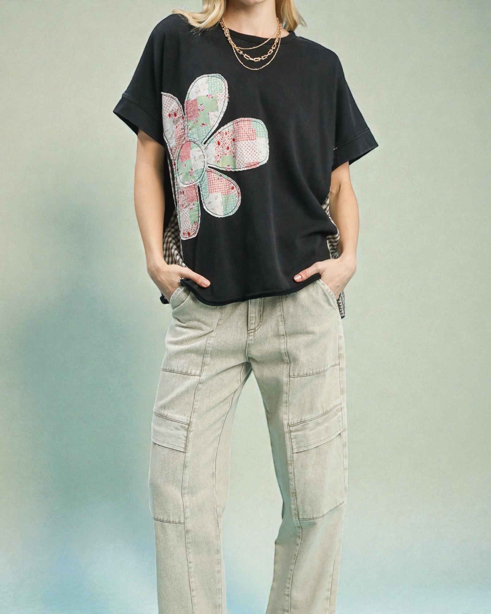 Person wearing a black t-shirt with a colorful flower design and beige cargo pants on a light background