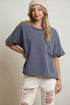 Woman wearing a blue oversized t-shirt and white distressed jeans on a plain background