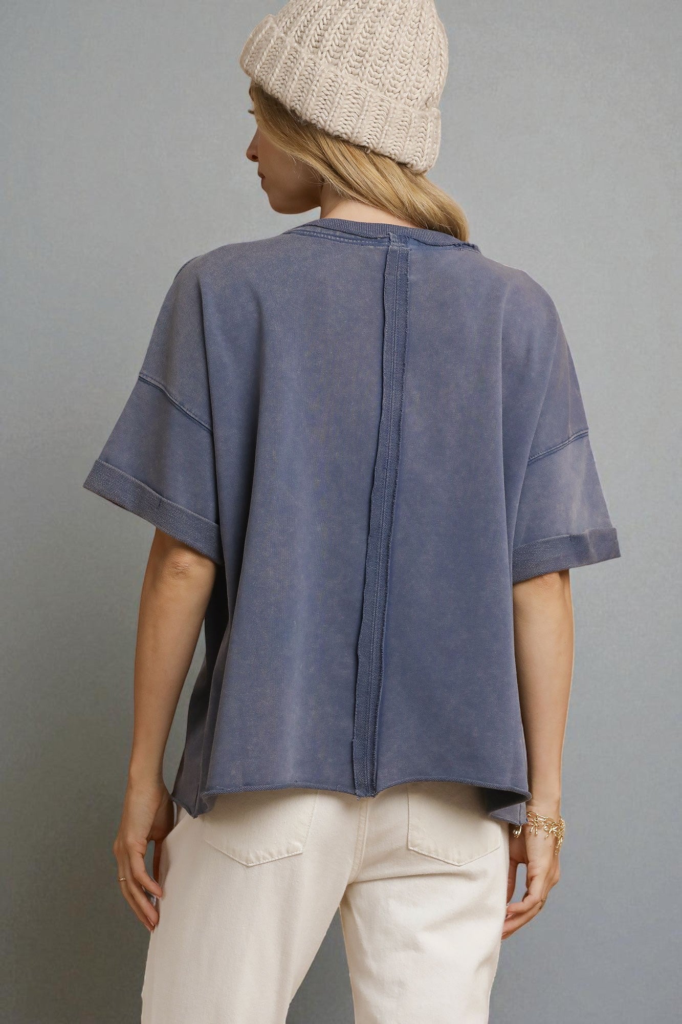 Person wearing a blue shirt and beige pants with a gray background