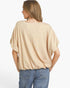 A woman shown from the back wearing a beige short-sleeve top and blue jeans against a plain white background.
