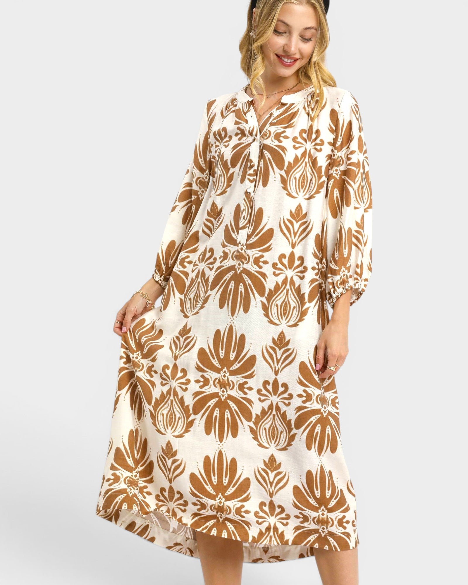 Woman wearing a white dress with brown floral pattern on a plain background