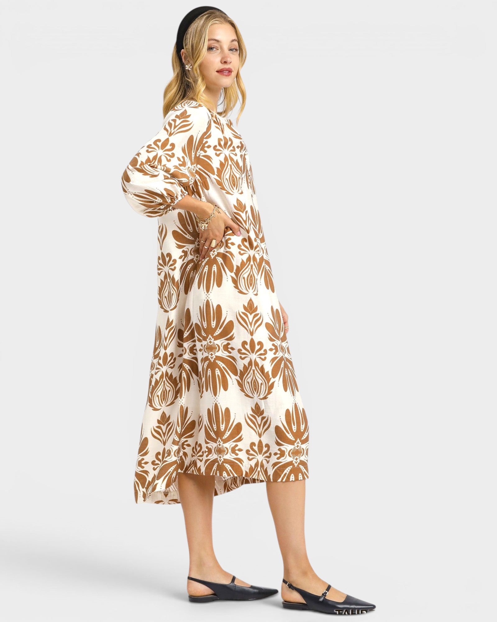 Woman wearing a white dress with brown floral pattern on a white background