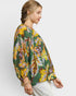 Woman wearing a colorful floral blouse against a white background