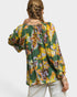 Woman wearing a colorful floral blouse with long sleeves on a white background
