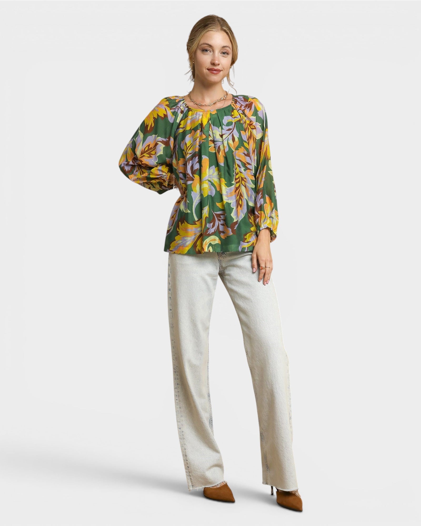 Woman wearing a floral blouse and white pants on a white background