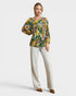 Woman wearing a floral blouse and white pants on a white background
