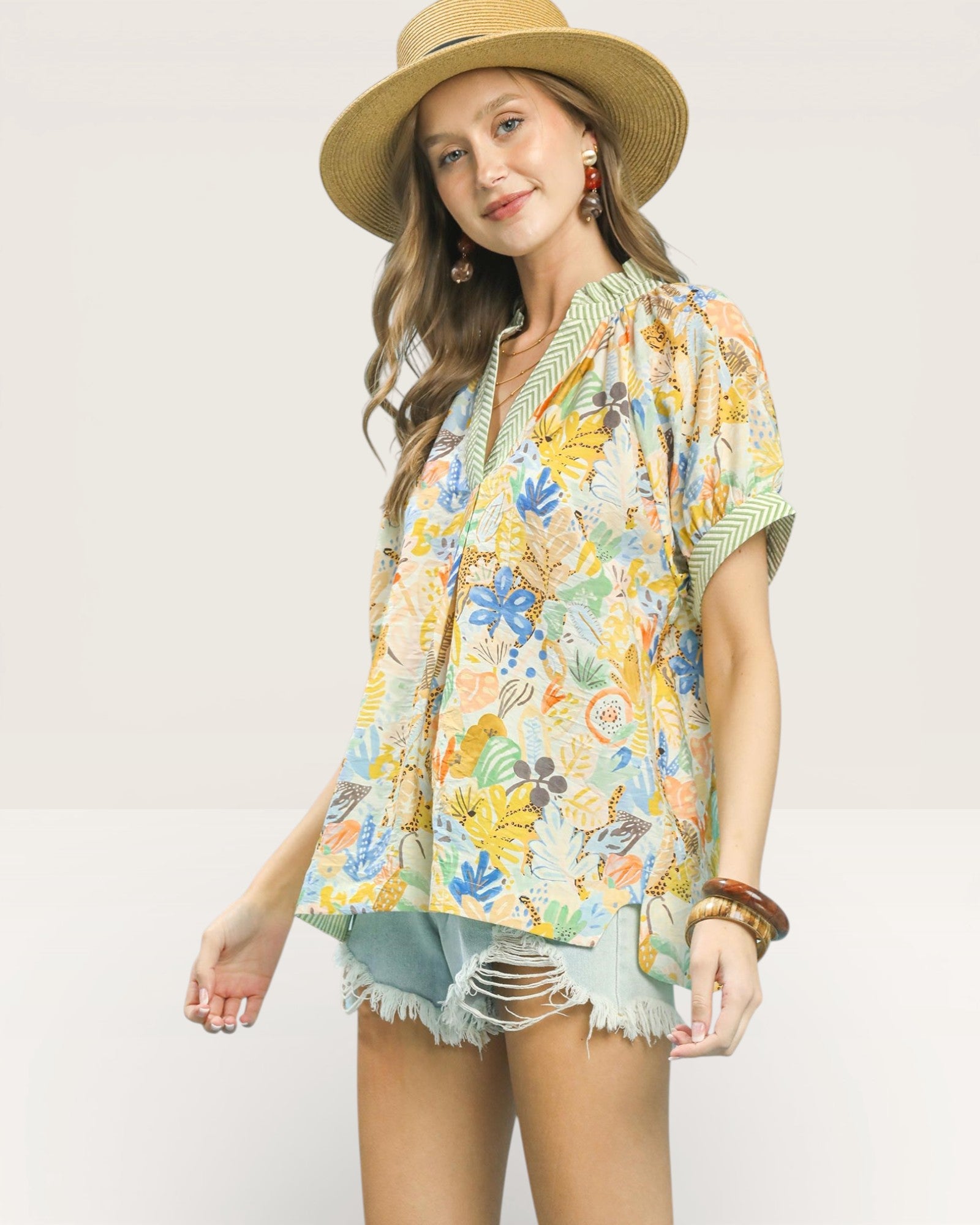 Woman wearing a colorful floral shirt and straw hat on a plain background