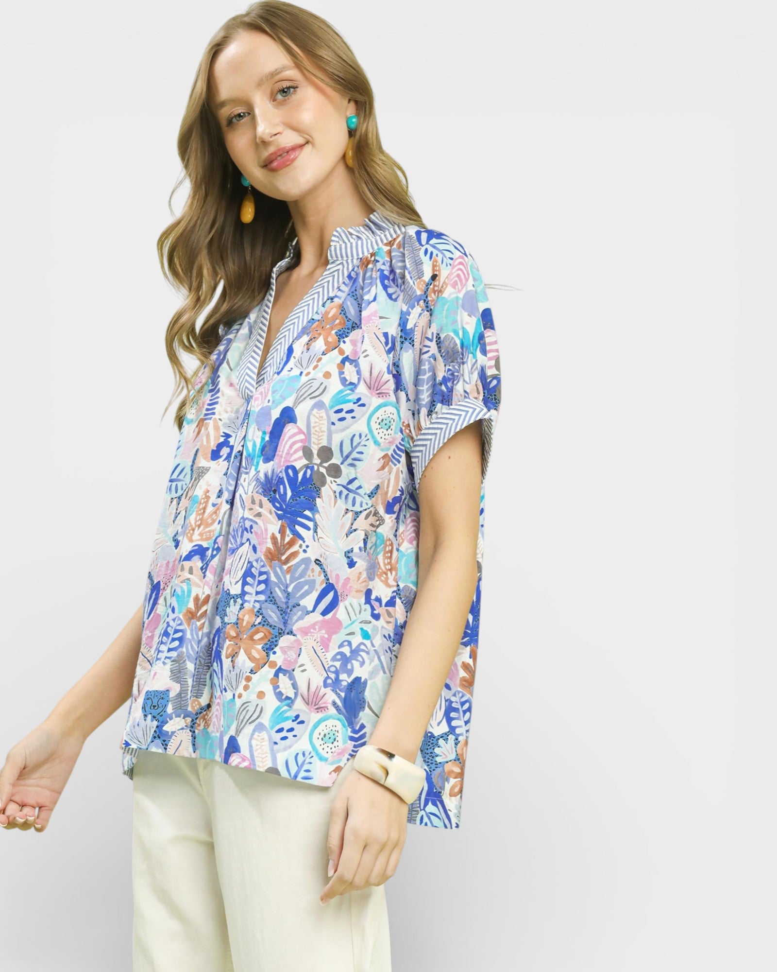 Woman wearing a colorful patterned blouse against a plain background