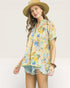 Woman wearing a colorful floral shirt and straw hat on a plain background