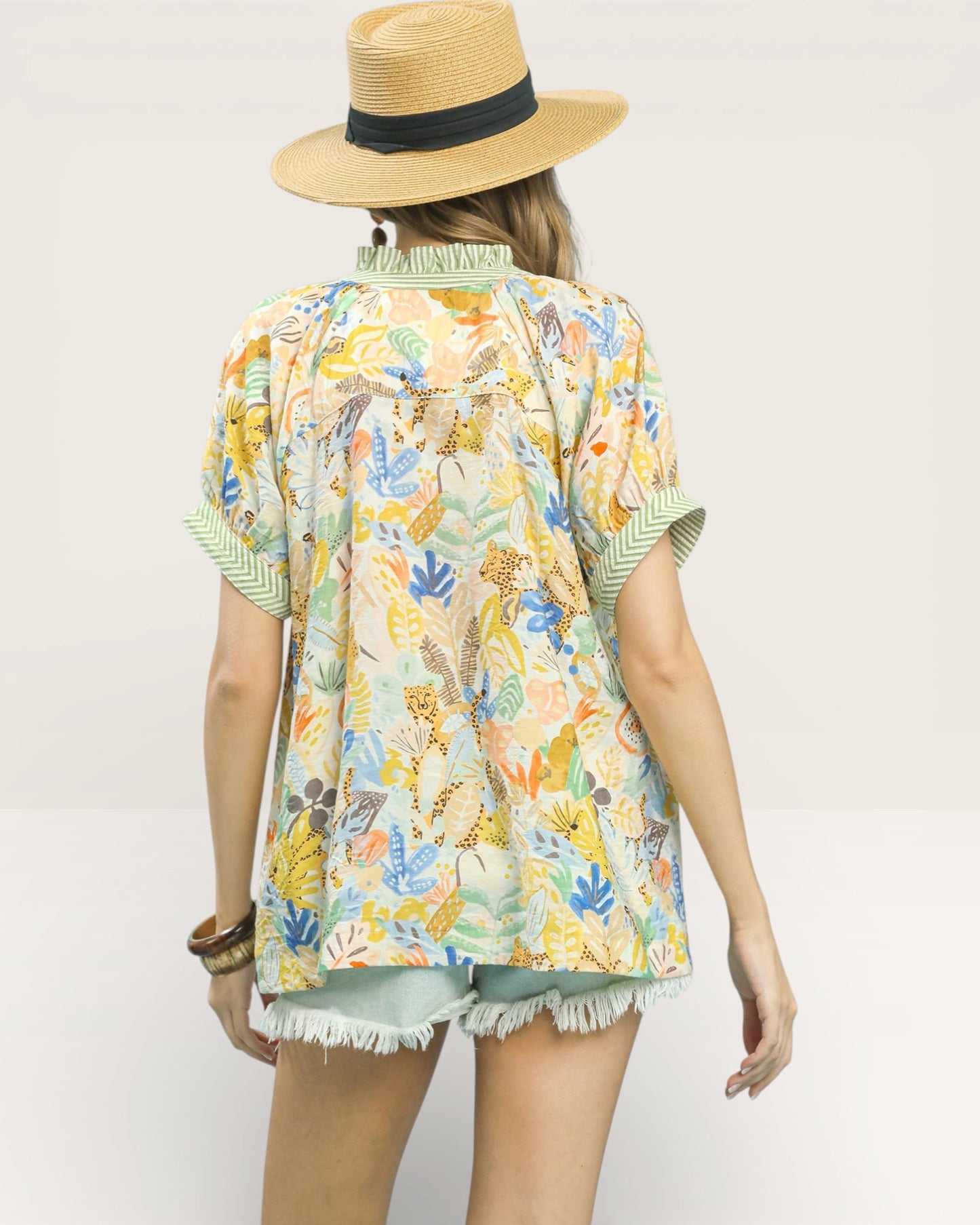 Person wearing a colorful patterned shirt and straw hat on a plain background