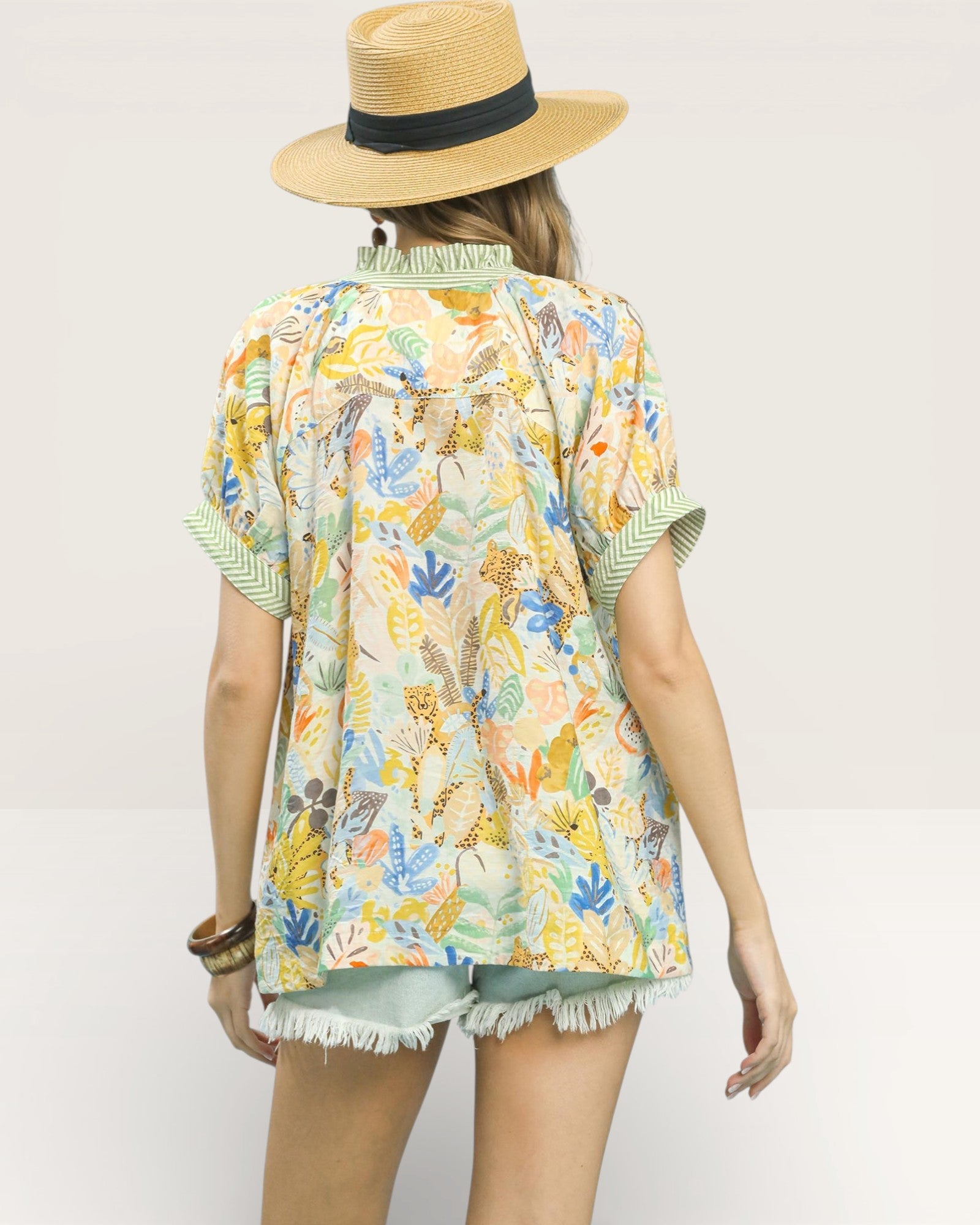 Person wearing a colorful patterned shirt and straw hat on a plain background