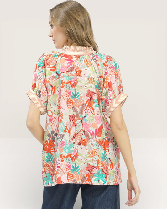 Woman wearing a colorful patterned blouse with a plain background