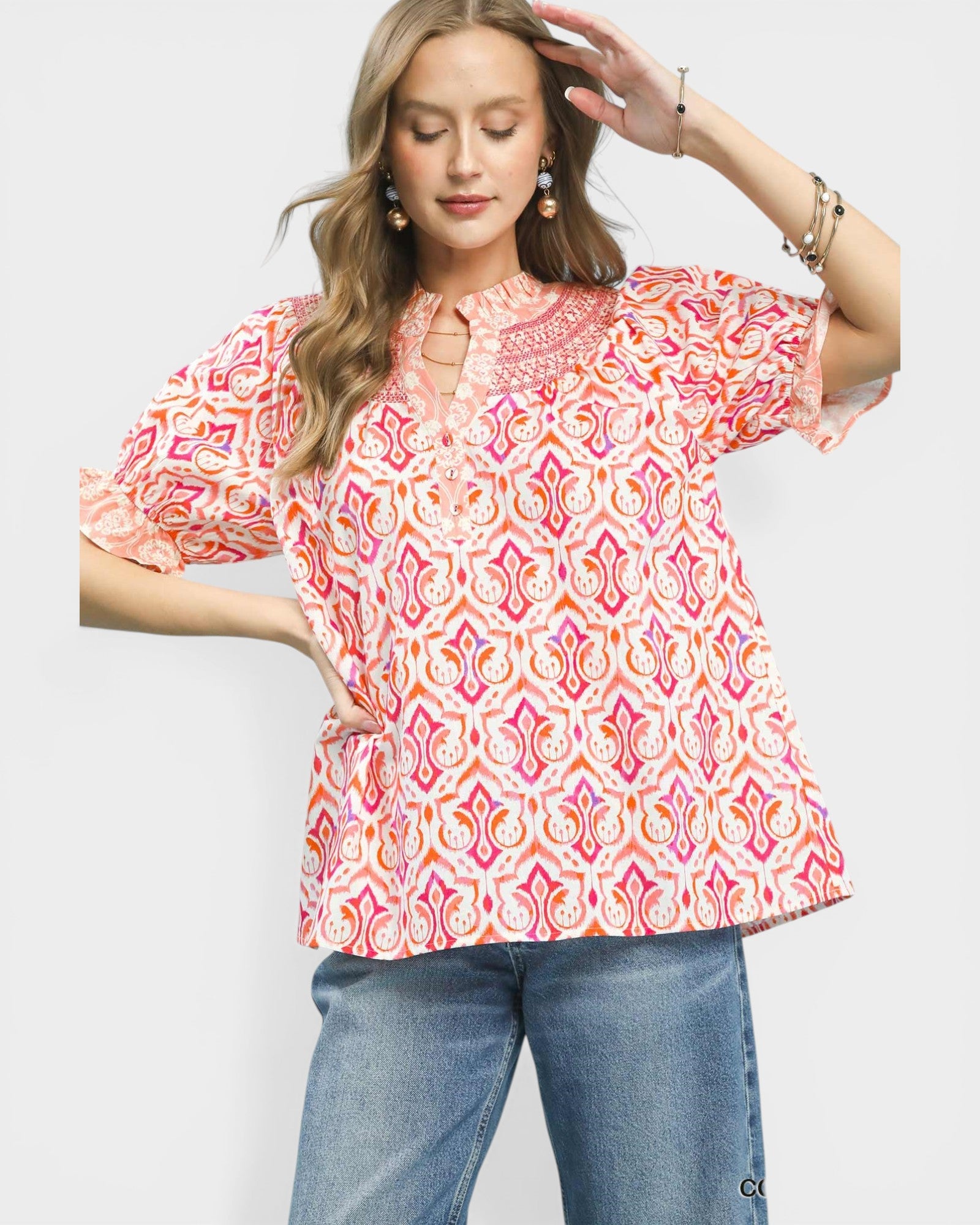 Woman wearing a colorful patterned blouse and jeans on a white background