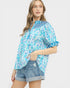 Woman wearing a blue and white patterned blouse with denim shorts on a white background