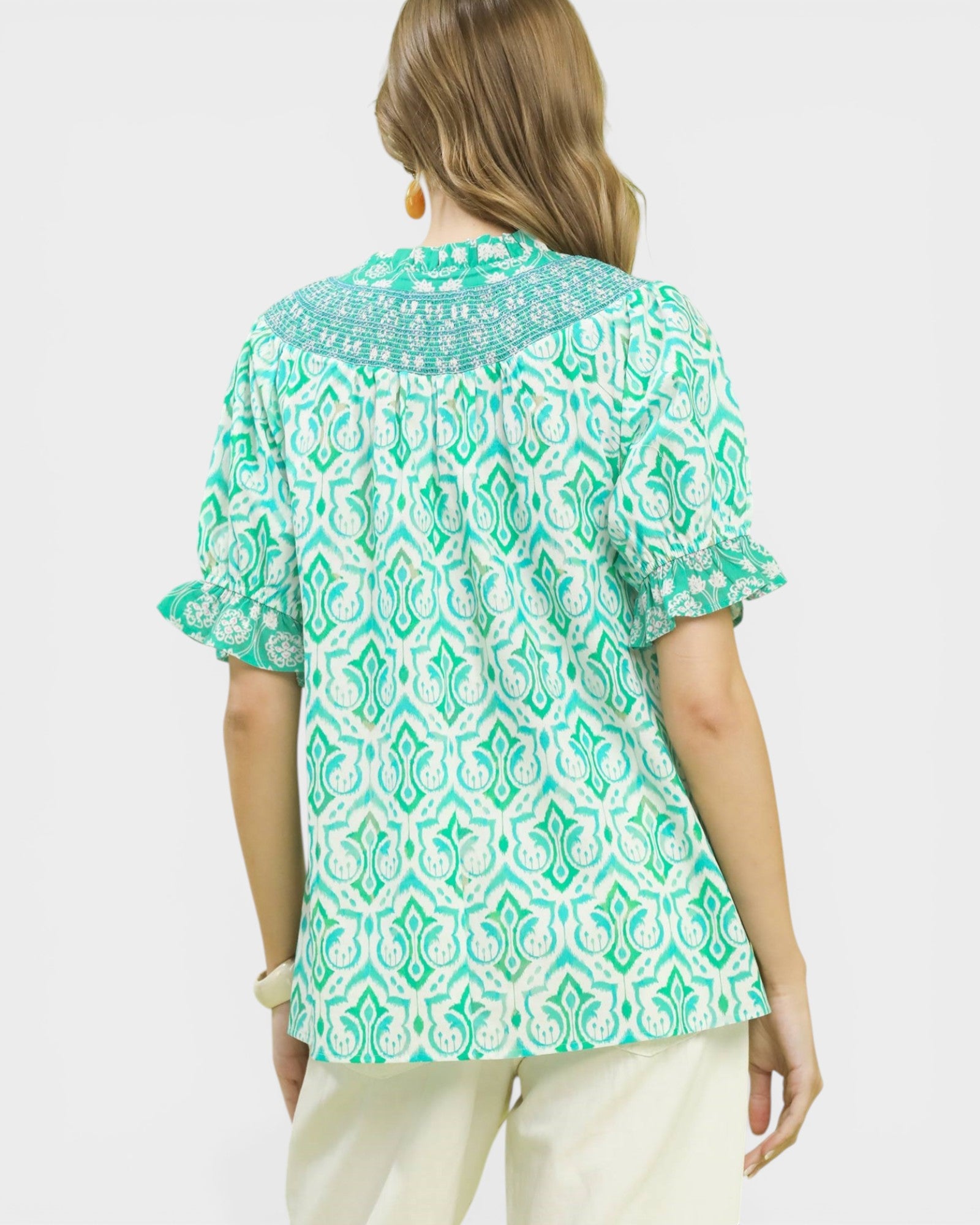 Woman wearing a green and white patterned blouse on a white background