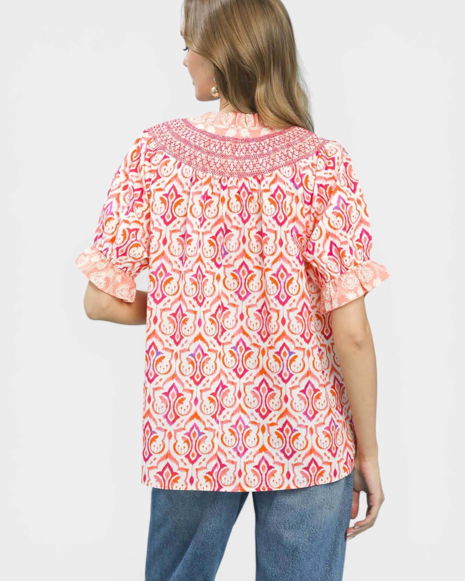 Woman wearing a colorful patterned blouse with short sleeves on a white background