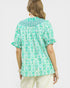 Woman wearing a green and white patterned blouse on a white background