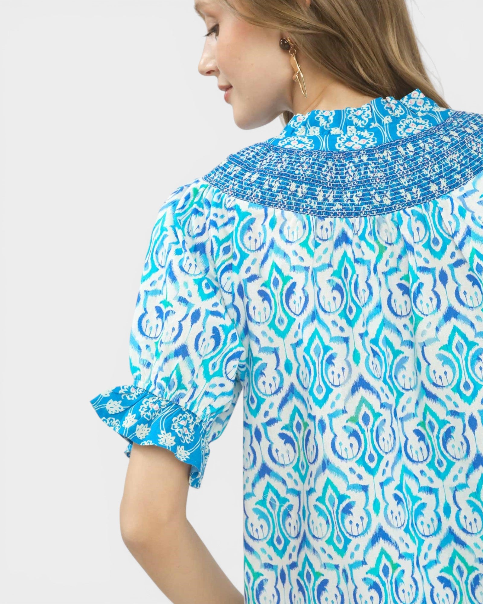 Woman wearing a blue and white patterned dress on a plain background