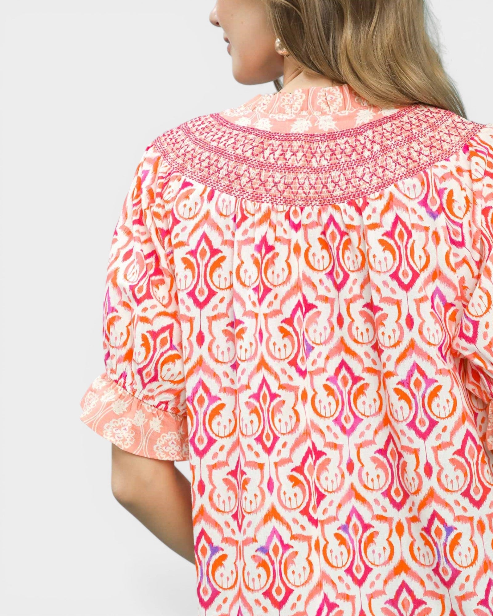 Woman wearing a colorful patterned blouse with a white background