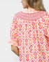 Woman wearing a colorful patterned blouse with a white background