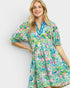 Woman wearing a colorful floral dress on a plain background