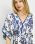 Woman wearing a blue and white patterned dress on a plain background