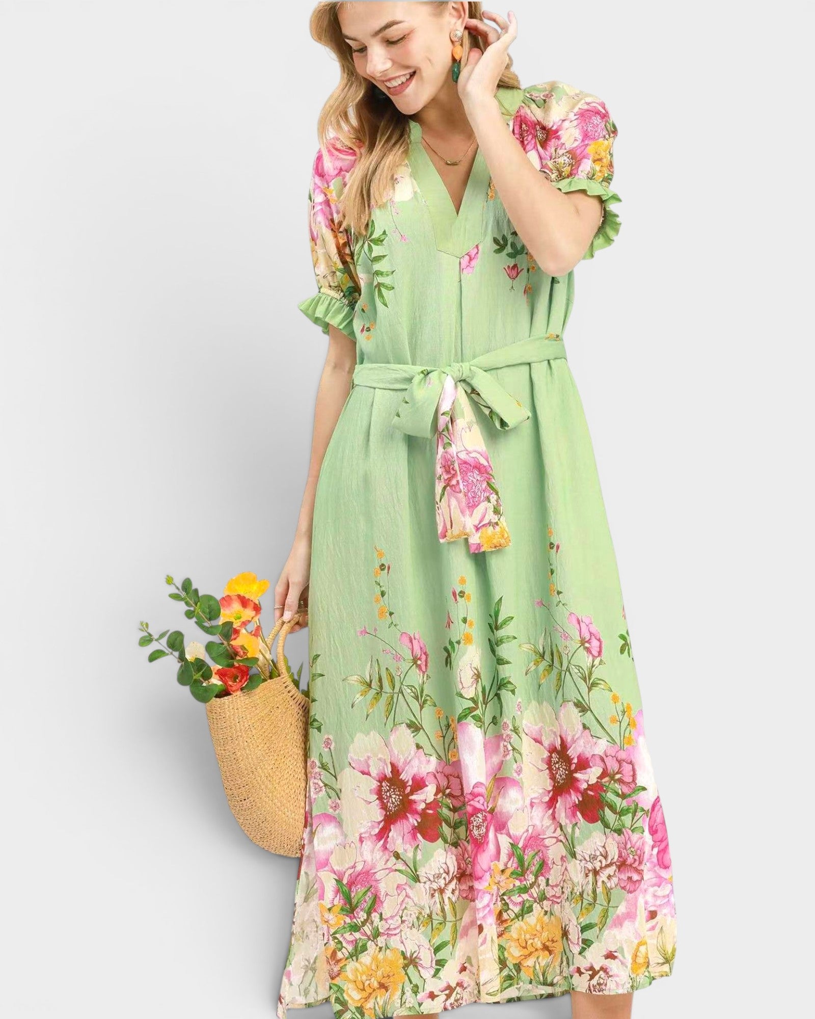 Woman wearing a green floral dress holding a basket of flowers against a white background