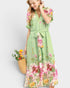 Woman wearing a green floral dress holding a basket of flowers against a white background