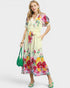 Woman wearing a floral dress with a green handbag on a white background
