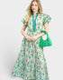 Woman wearing a floral dress holding a green handbag on a white background