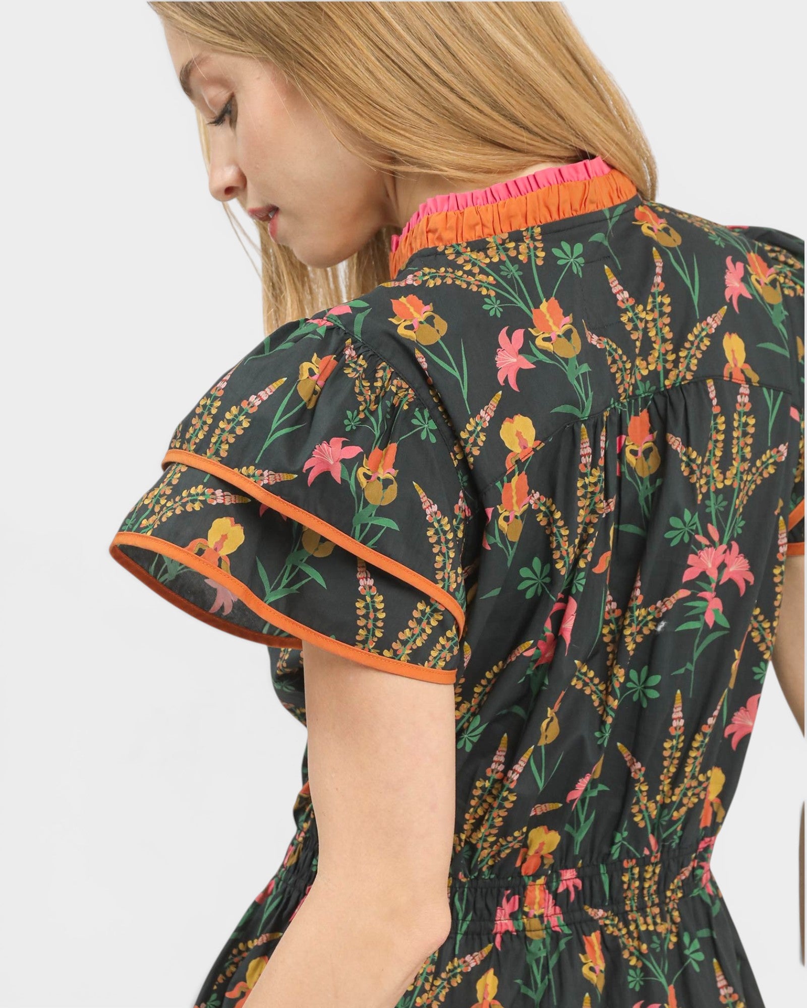 Woman wearing a floral dress with colorful trim on a white background