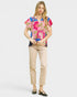 Woman wearing a colorful floral blouse and beige pants on a white background