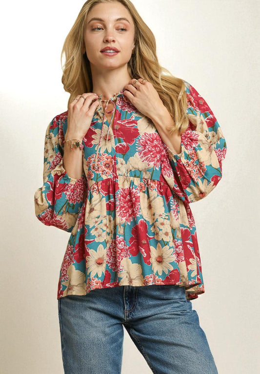 Woman wearing a colorful floral blouse and jeans on a beige background