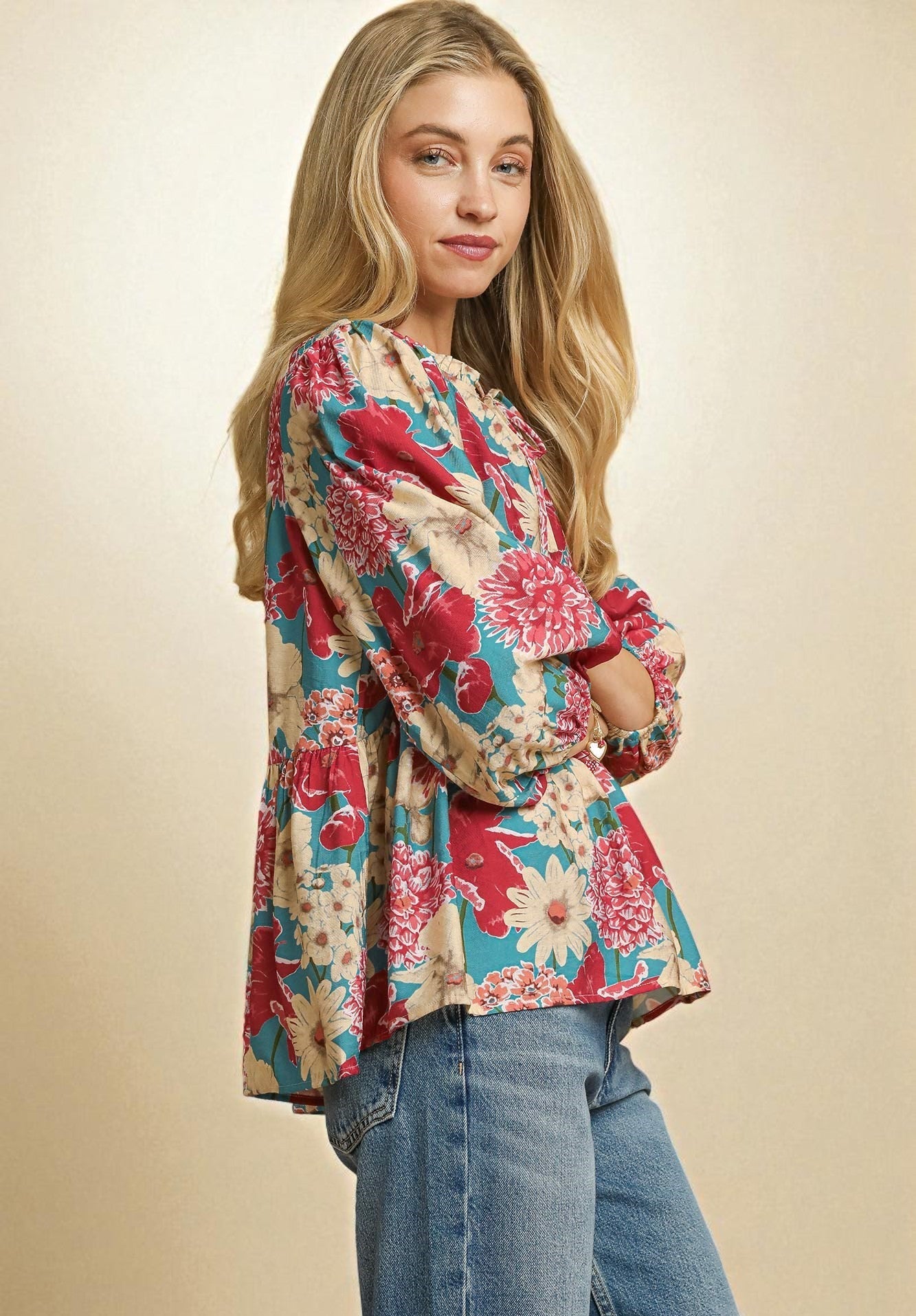 Woman wearing a colorful floral blouse and jeans on a beige background