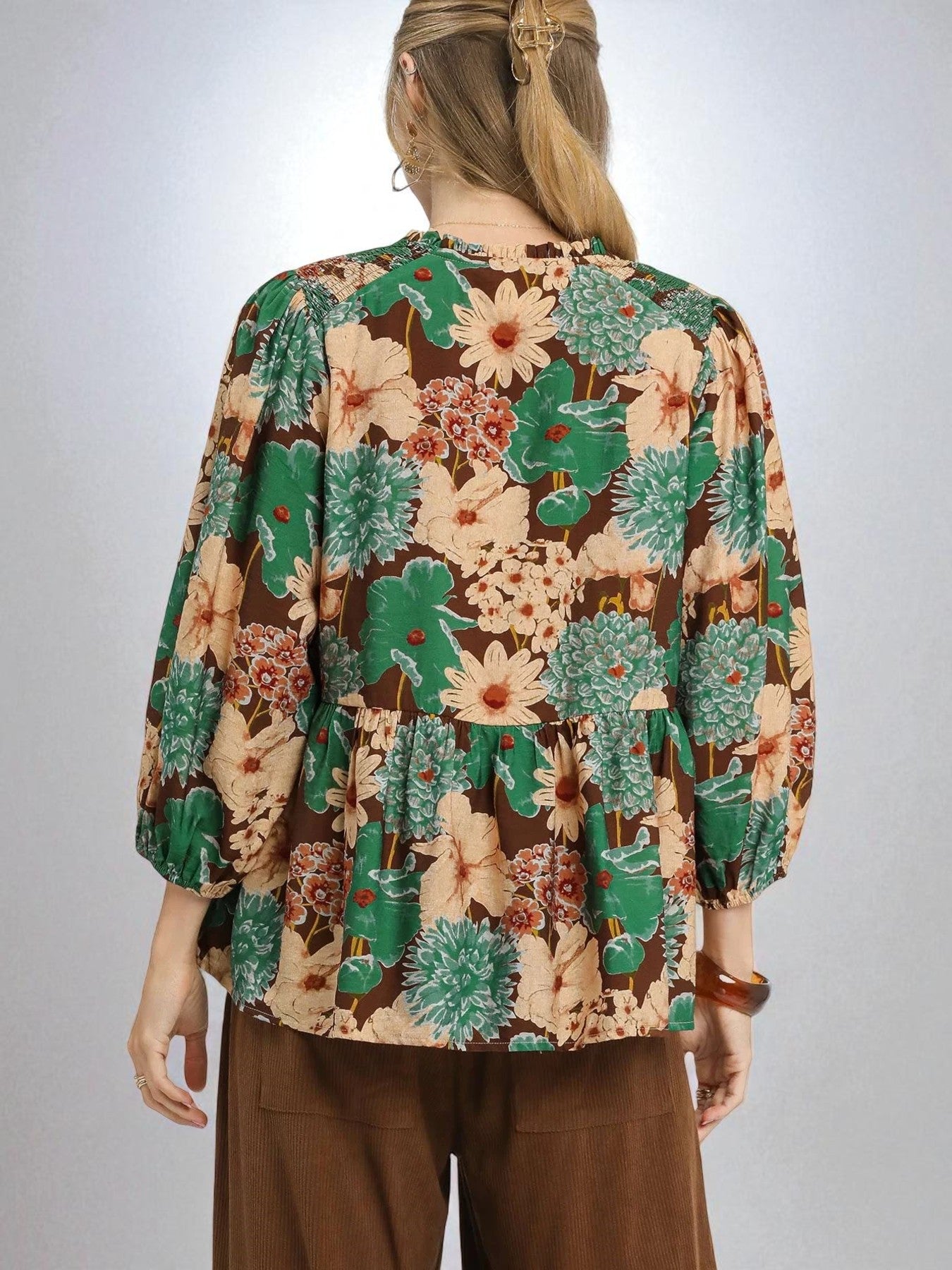 Person wearing a floral blouse with a plain background
