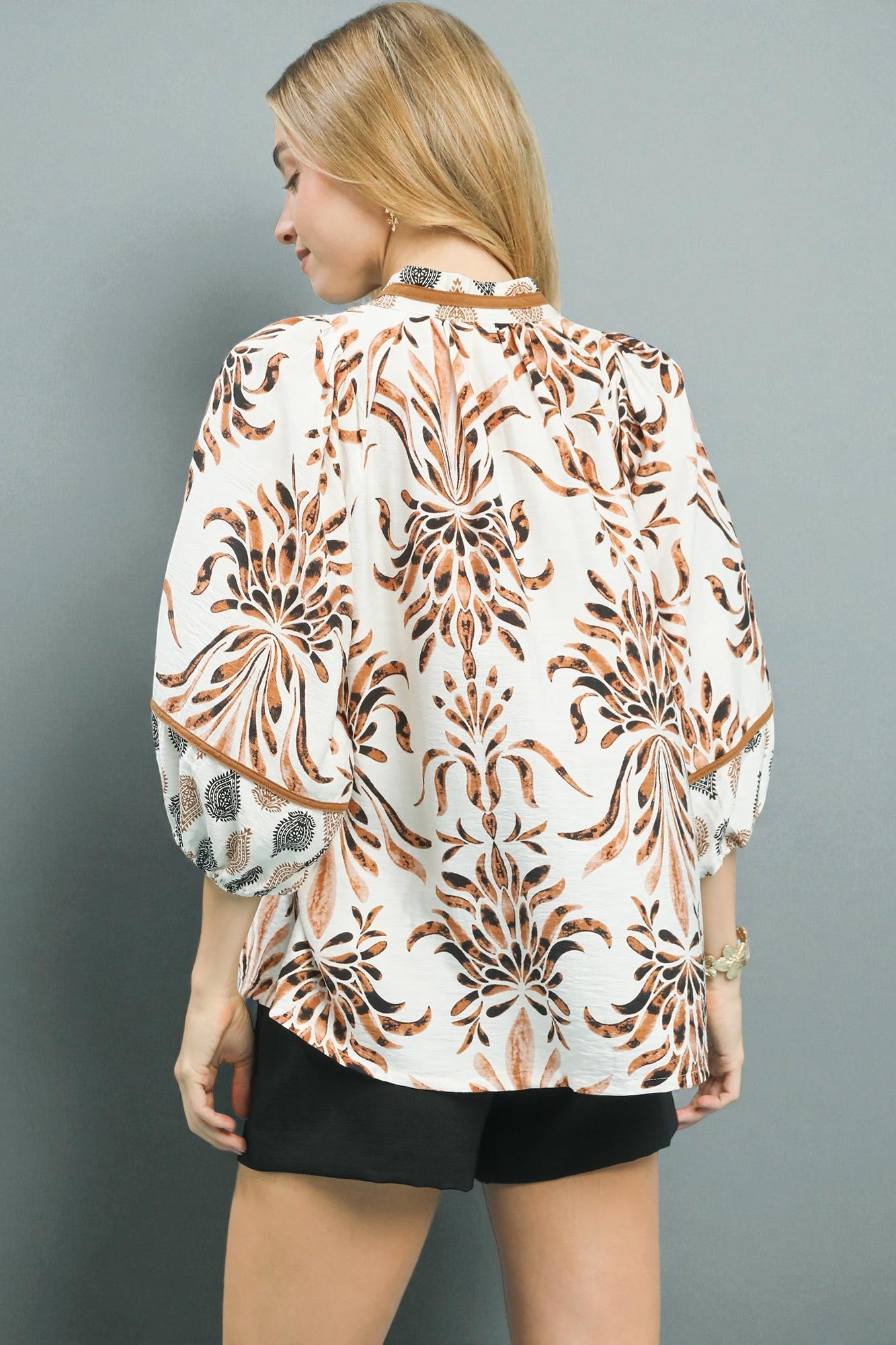 Woman wearing a patterned blouse with a gray background