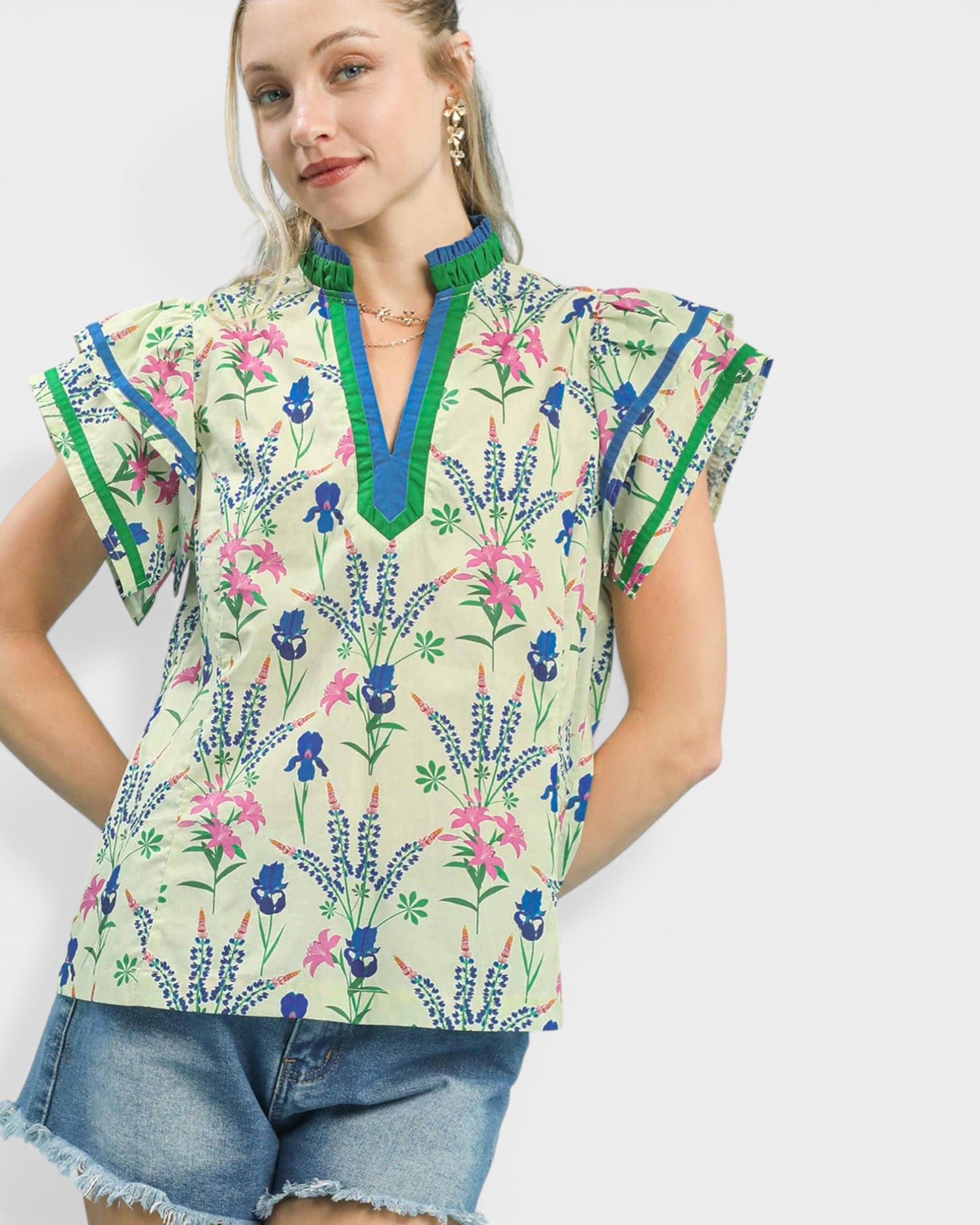 Woman wearing a colorful floral blouse with ruffled sleeves on a white background