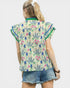 Woman wearing a colorful floral-patterned shirt with denim shorts on a white background