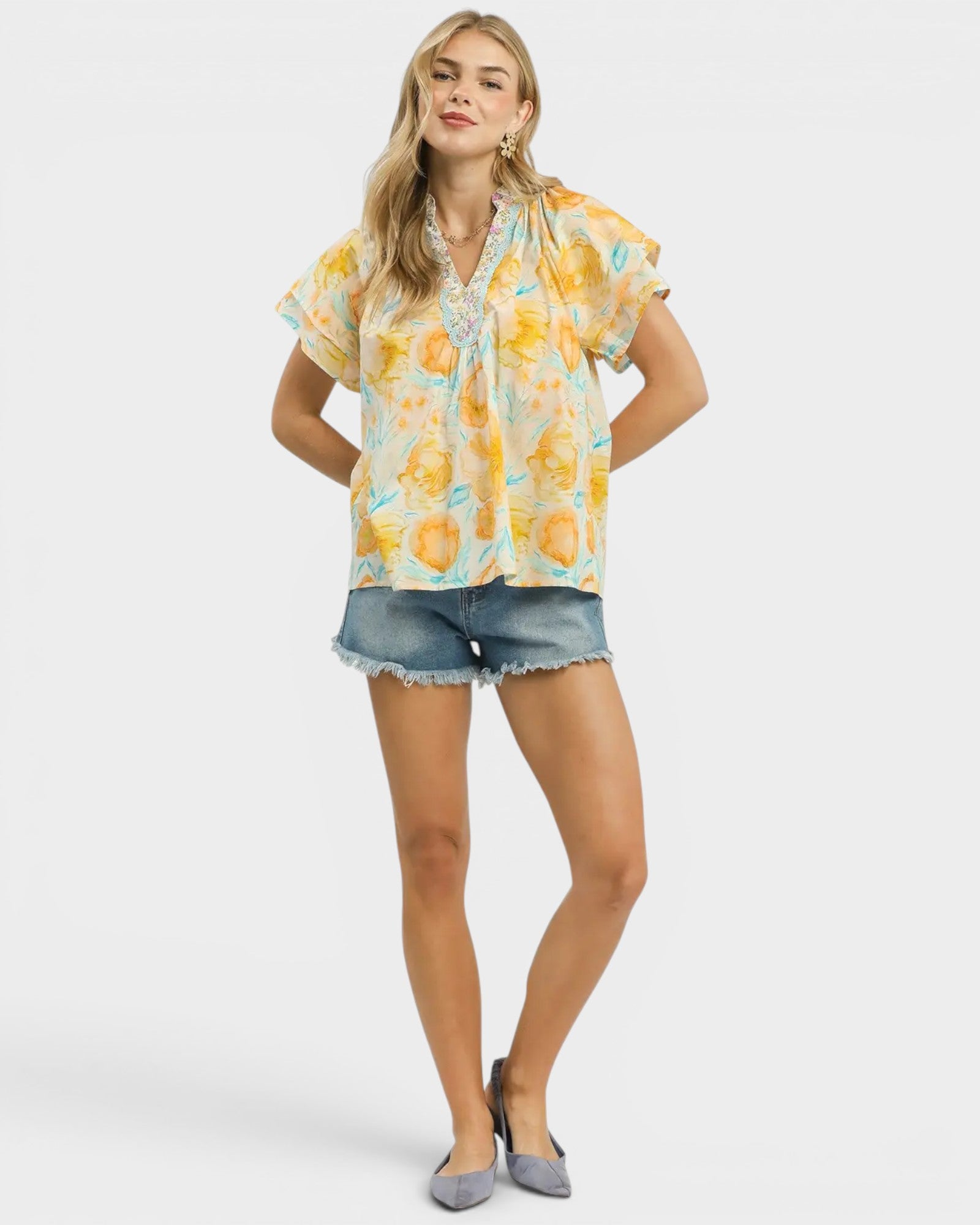 Woman wearing a floral blouse and denim shorts on a white background