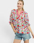Woman wearing a colorful floral blouse and denim shorts on a white background
