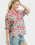 Woman wearing a colorful floral blouse and denim shorts on a white background