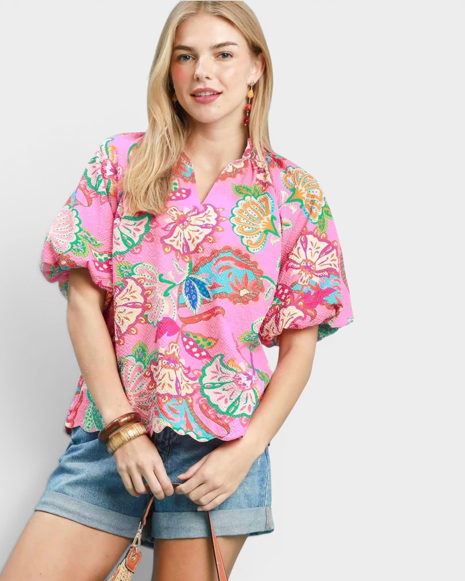 Woman wearing a colorful floral blouse and denim shorts on a white background