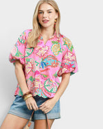 Woman wearing a colorful floral blouse and denim shorts on a white background