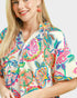 Woman wearing a colorful butterfly patterned shirt on a white background