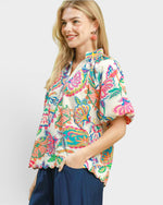 Woman wearing a colorful floral blouse against a white background