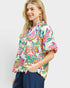 Woman wearing a colorful floral blouse against a white background